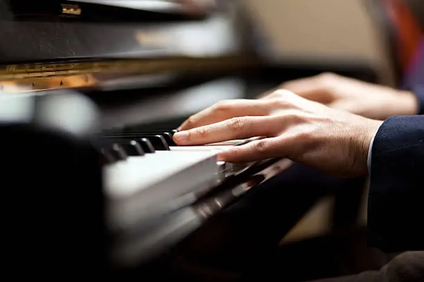 Delle mani suonano i tasti di un pianoforte, mostrando un momento di concentrazione musicale.