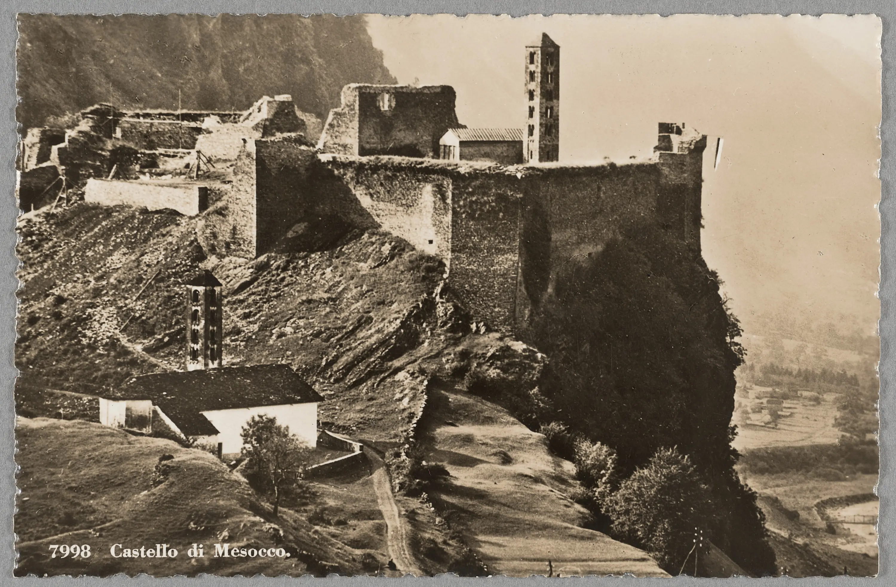 Castello di Mescocco situato su una scogliera, con rovine e torri visibili. Paesaggio montano sullo sfondo.