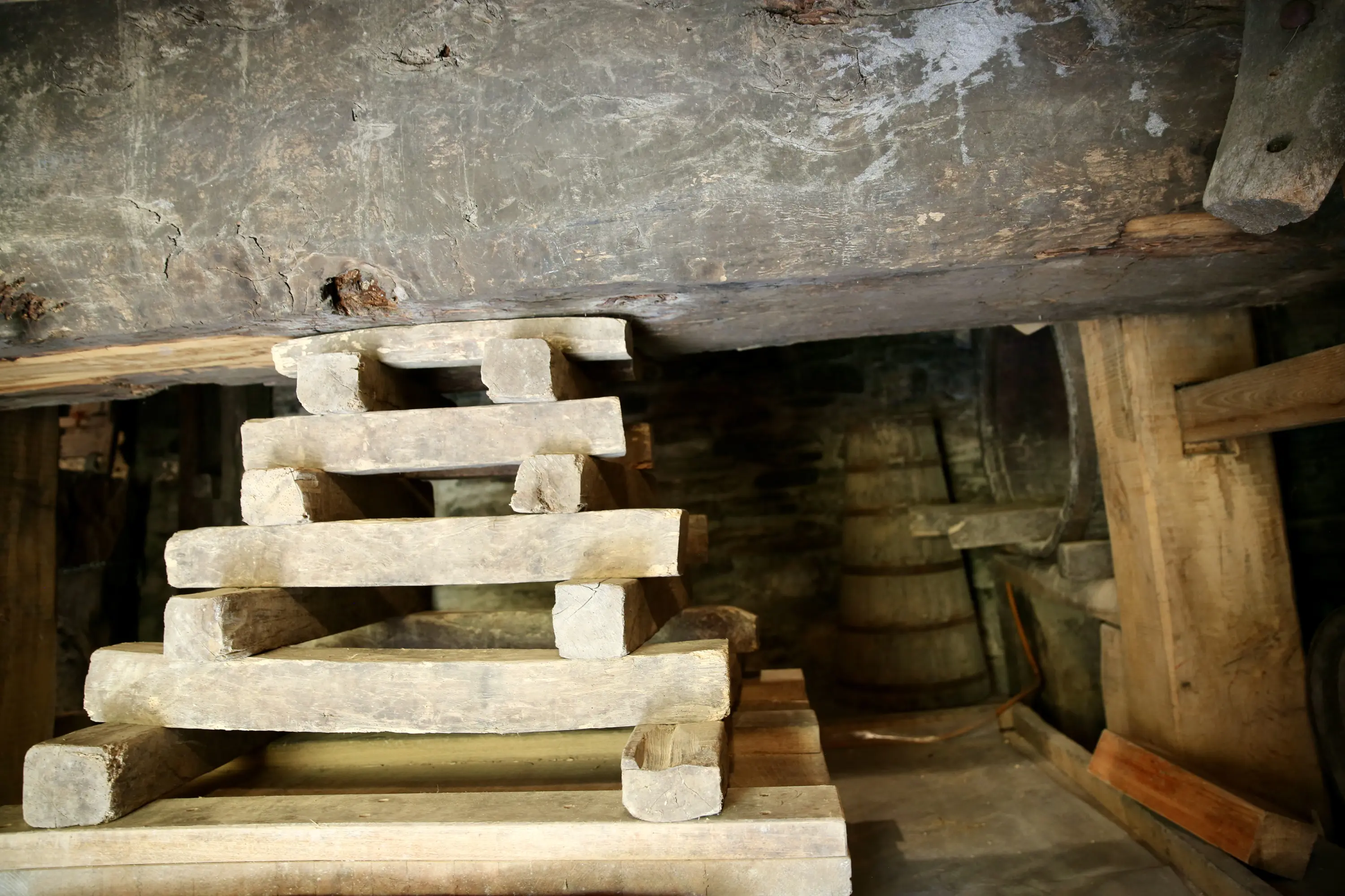 Struttura in legno con gradini, posizionata in un ambiente rustico e buio, con pareti e soffitto in pietra.