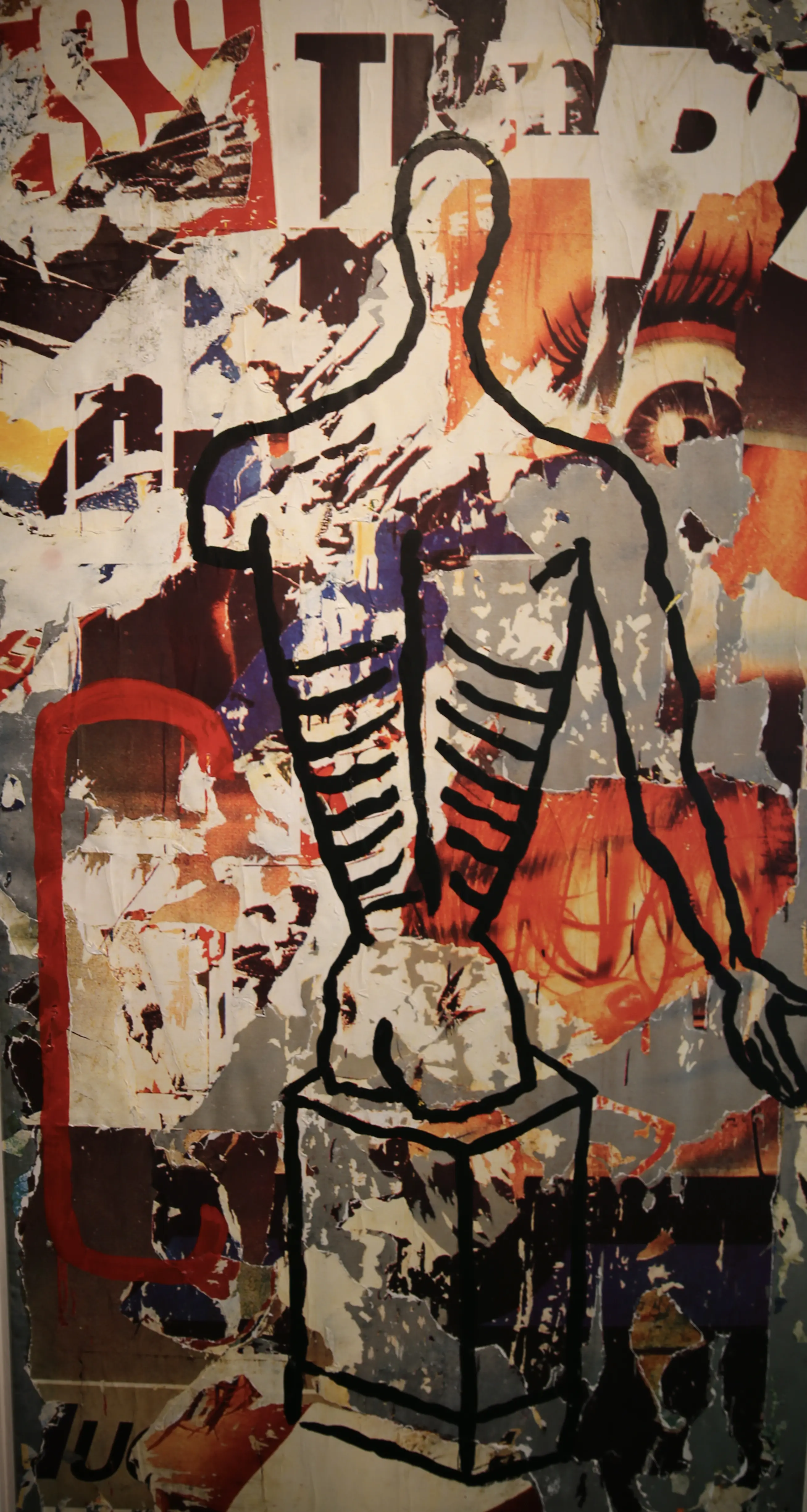 Un murale che rappresenta un torso umano stilizzato, con una schiena e una gabbia toracica delineate. Sullo sfondo sono visibili pezzi di collage con colori vivaci e immagini di occhi e testi.