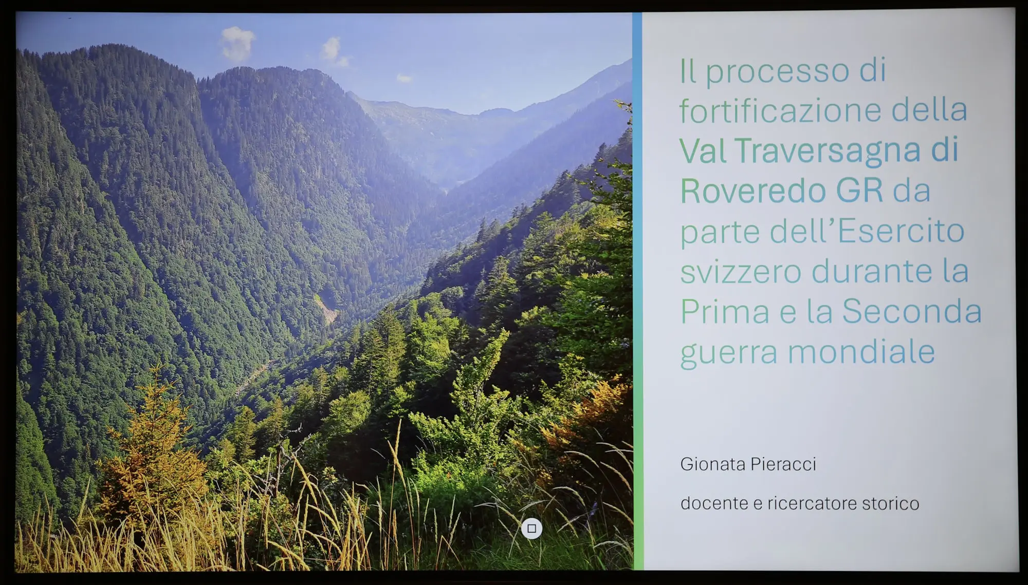 Panorama montano della Val Traversa di Roveredo con valli verdi e alberi, accompagnato da un testo informativo sul processo di fortificazione della zona durante le guerre mondiali.