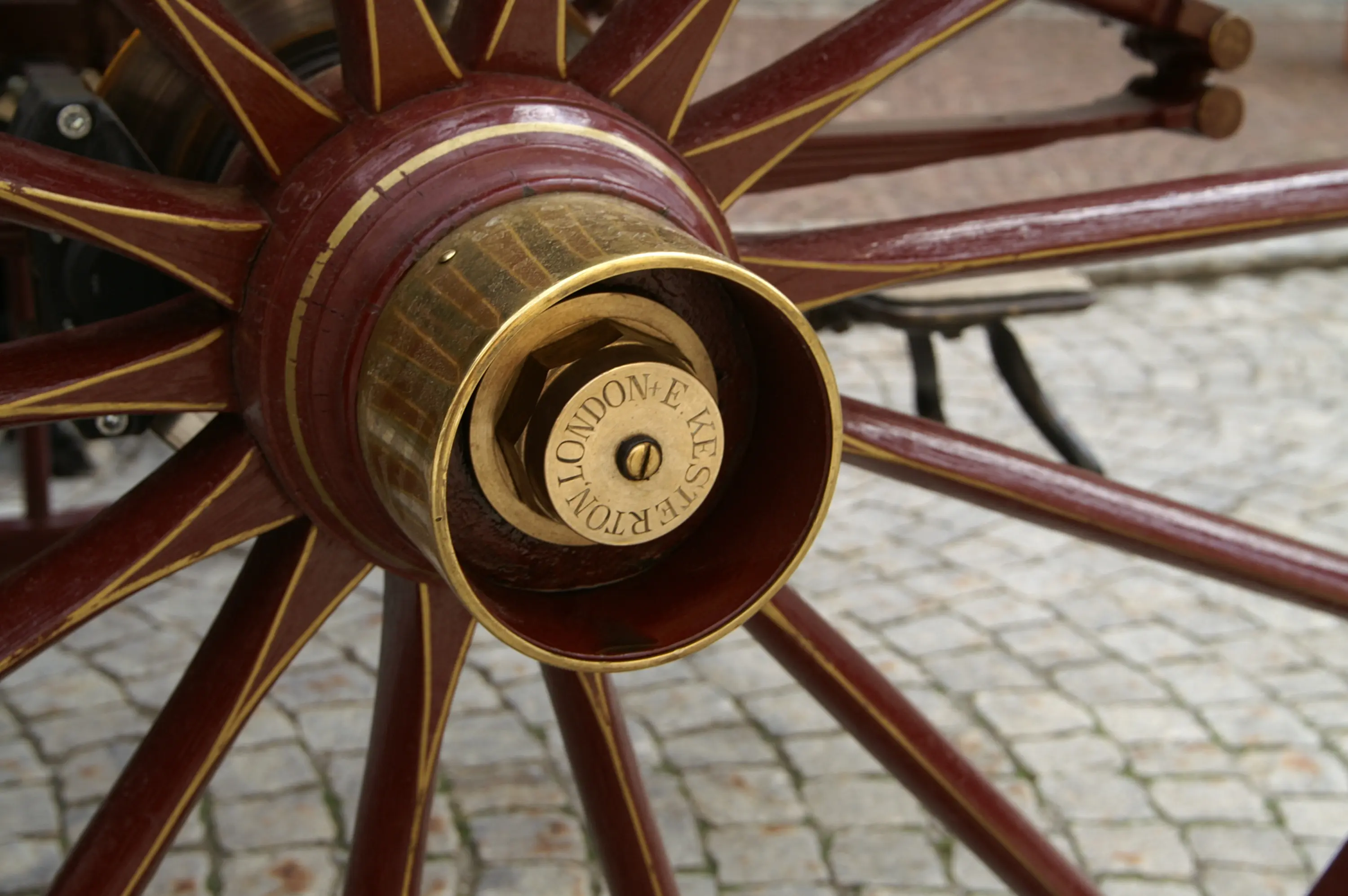 Ruota di un'antica carrozza, con una parte centrale in ottone brillante che riporta la scritta "London & Yorkshire Railway". Il legno della ruota è di un rosso ricco, con dettagli dorati.