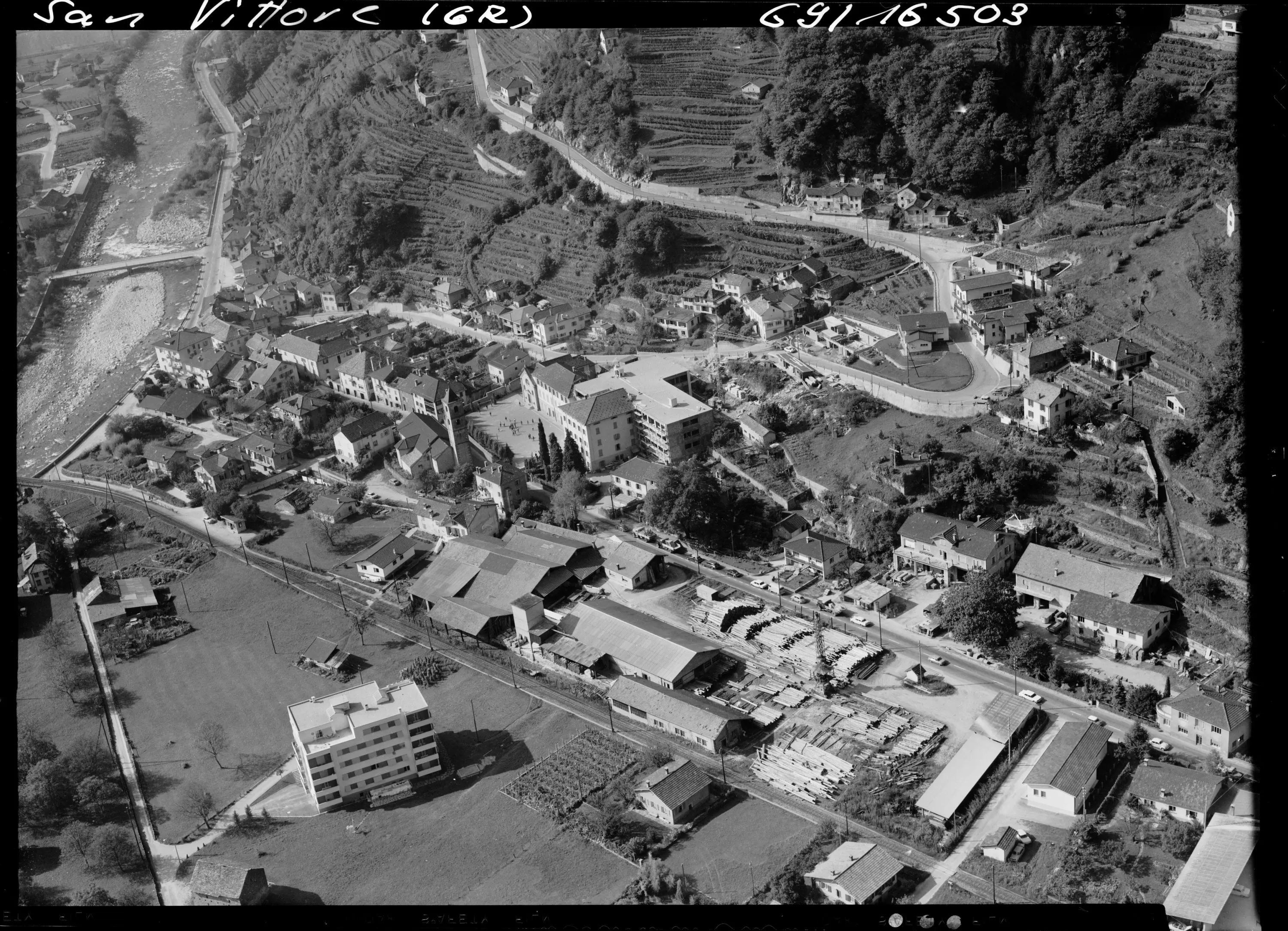 Veduta aerea del paese di San Vittore, con la disposizione delle case, strade e attività commerciali. Si possono notare le aree verdi circostanti e i pendii collinari.